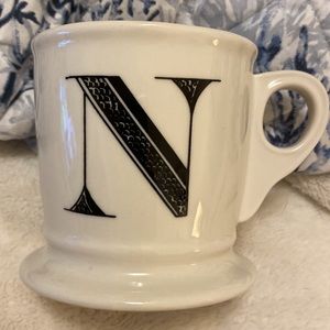 Black and white decorative mug with the capital letter N stamped on the bottom